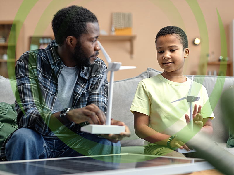 African American father teaching son on renewable energy sources and holding wind turbine model